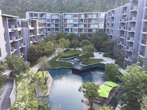 Ein moderner Wohnkomplex mit mehreren Hochhäusern, einer zentralen Grünanlage mit Wasserspiel und Außenmöbeln.
