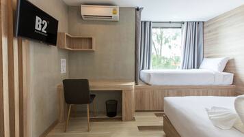 Una habitación de hotel con cama, escritorio, silla, televisor y aire acondicionado.
