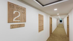 A hotel hallway with wooden number signs indicating room 2nd floor, doors, and a carpeted floor. - B2 Ubon Premier Hotel (Ubon Ratchathani)