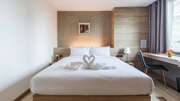 Una habitación de hotel con una cama bien hecha, un escritorio con una silla y una ventana con cortinas.