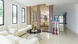 A modern living room with a white sofa, a glass coffee table, and two potted plants. - B2 Ubon Premier Hotel (Ubon Ratchathani)