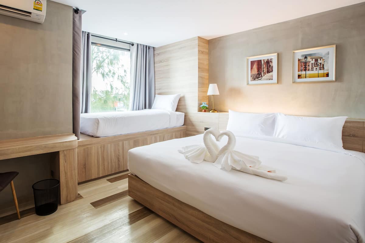 A hotel room with a bed, a desk, a chair, and two framed pictures on the wall.