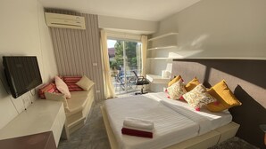A hotel room with a bed, a desk, a TV, and a balcony with a table and chairs. - Condo Studio B at Replay E305 (Koh Samui)