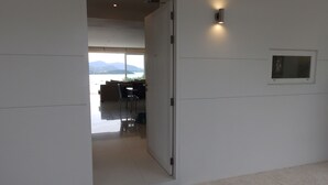 A modern interior with a sliding door leading to a dining area with a view of mountains. - Condo Studio B at Replay E305 (Koh Samui)