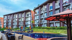 A modern hotel with a pool area, outdoor seating, and a well-maintained garden. - Condo Studio B at Replay E305 (Koh Samui)