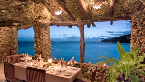 A table set for dining with a view of the sea and a stone structure. - Savasi Island Resort (Savusavu)
