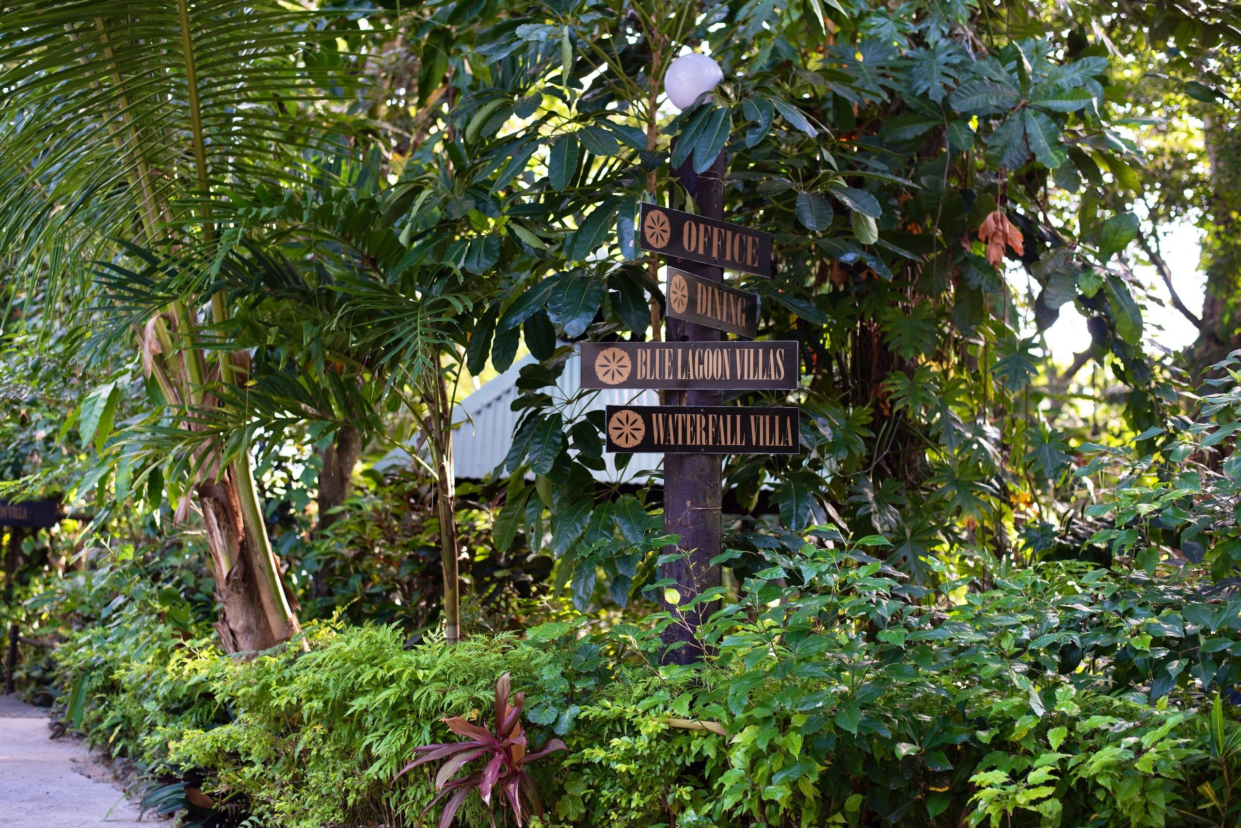 A signpost with directions to 'Office', 'Dining', 'Blue Lagoon Villas', and 'Waterfall Villa'.