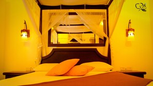 Una cama con dosela, dos lámparas de noche y una mesita.
