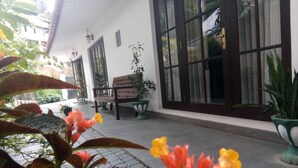 Un espacio al aire libre cubierto con un banco, plantas en macetas y piso de baldosas.