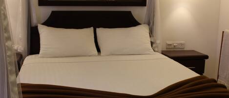 A bed with a canopy, a bedside table, and a wall-mounted light fixture.