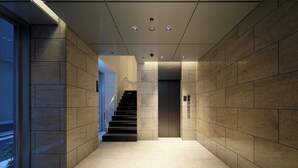 A modern elevator lobby with a tiled floor and walls, a staircase, and a door with an elevator control panel. - Keio Presso Inn Tokyo Station Yaesu (Tokyo)