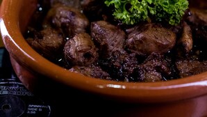 Une vue rapprochée d’un plat composé de viande et d’une garniture, servi dans un bol marron.