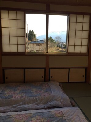 Una habitación con cama, ventana con paneles shoji y vista a la montaña.
