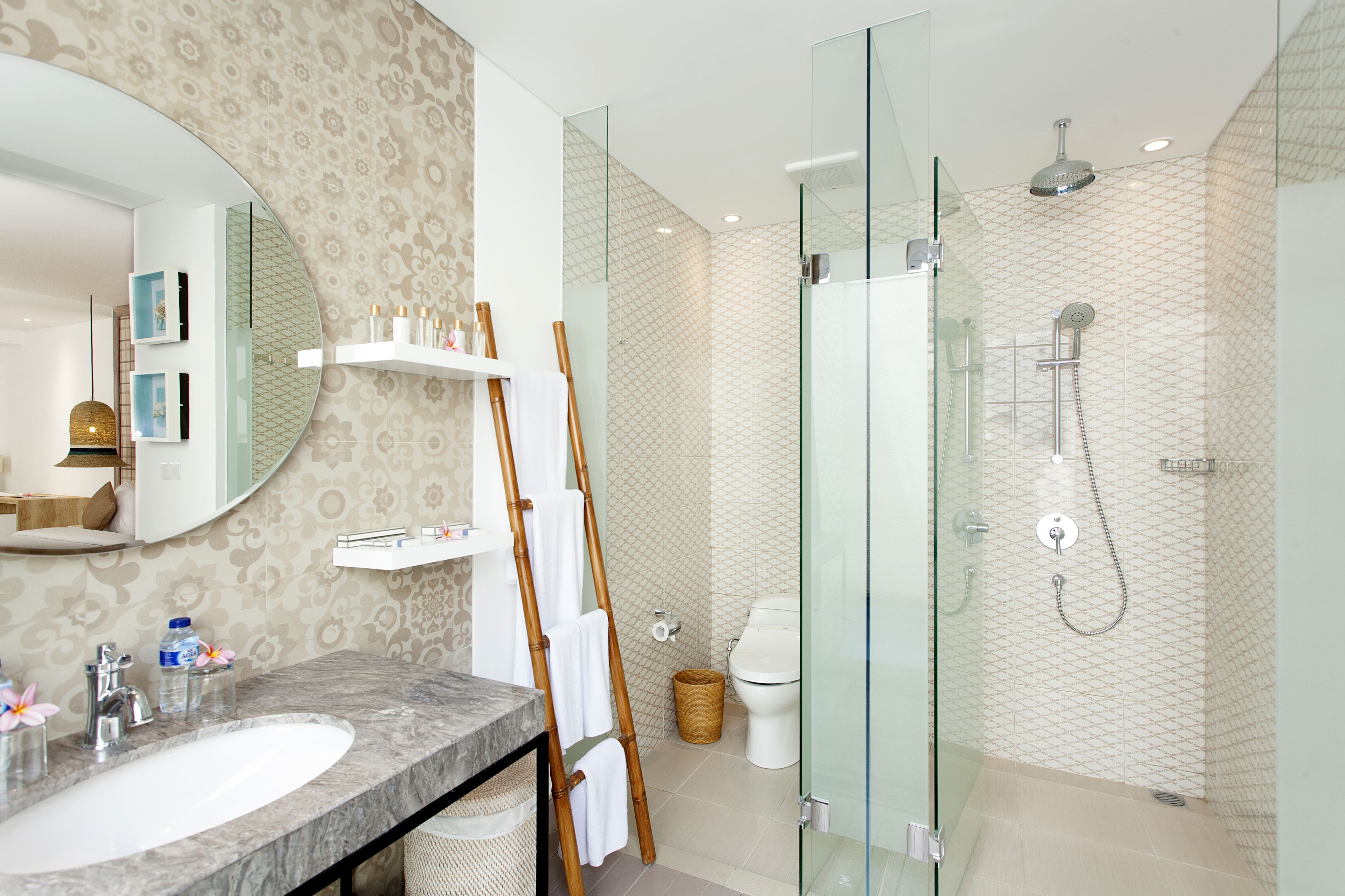 Un baño moderno con lavamanos de mármol, cabina de ducha con paredes de vidrio y papel tapiz estampado.