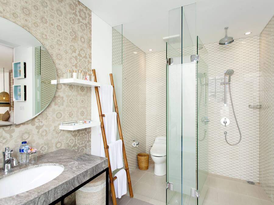 Un baño moderno con lavamanos de mármol, cabina de ducha con paredes de vidrio y papel tapiz estampado.