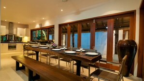 Un espace repas moderne avec une longue table en bois, dressée pour quatre personnes, entourée de chaises.