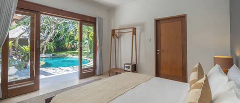 Un dormitorio con cama, armario de madera, sillón colgante y vista a una piscina.