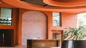 Un hall con un papel tapiz estampado, una recepción y una planta en maceta.