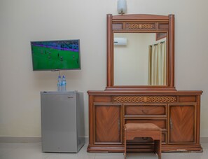 A room with a television mounted on the wall, a small refrigerator, and a wooden dresser with drawers. - Miika Eco Resort Hotel (Hoima)