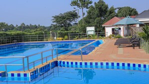 Ein Swimmingpool mit klarem, blauem Wasser, umgeben von einer gefliesten Liegefläche und Metallgeländern.