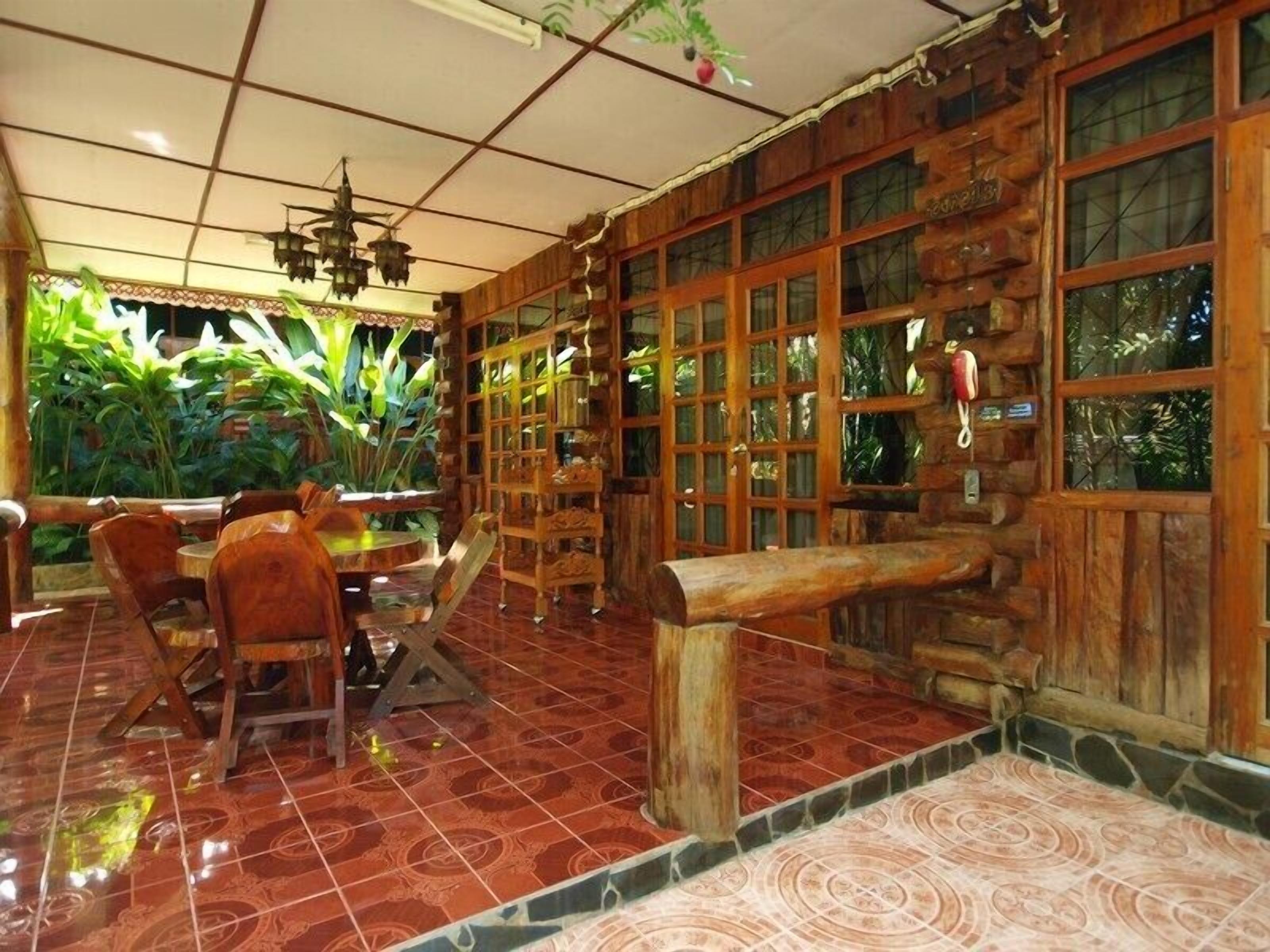 Un intérieur rustique avec des murs en bois, de grandes fenêtres et un sol carrelé.