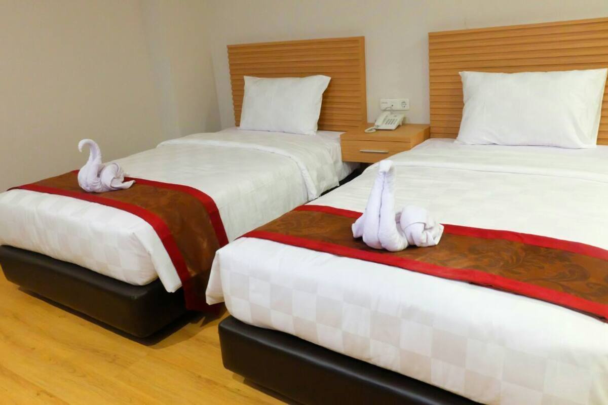 Two twin beds with wooden headboards, white bedding, and red and brown decorative pillows.