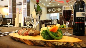 A dining table with a plate of food, a bottle of wine, and several glasses. - Heyday Hotel (Addis Ababa)