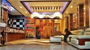 A lobby with a reception desk, a chandelier, a staircase, and a seating area. - Heyday Hotel (Addis Ababa)