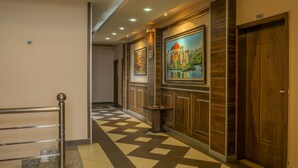 A hotel corridor with a patterned floor, wooden paneling, and artwork on the walls. - Heyday Hotel (Addis Ababa)