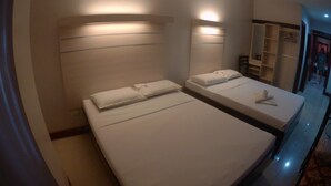 Habitación de hotel con dos camas, un armario y un espejo.