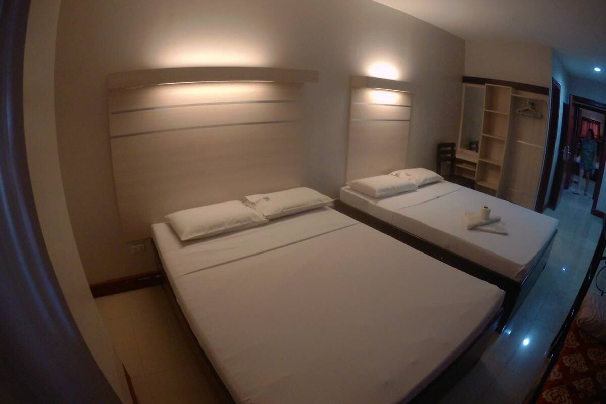 A hotel room with two beds, a wardrobe, and a mirror.