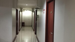 Un pasillo largo y estrecho con puertas a ambos lados, piso de baldosas y una lámpara en el techo.