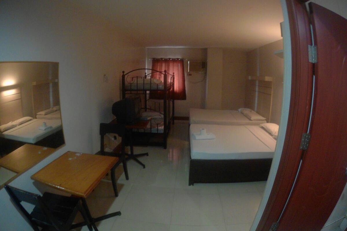 A small, compact room with a single bed, a desk, and a chair.
