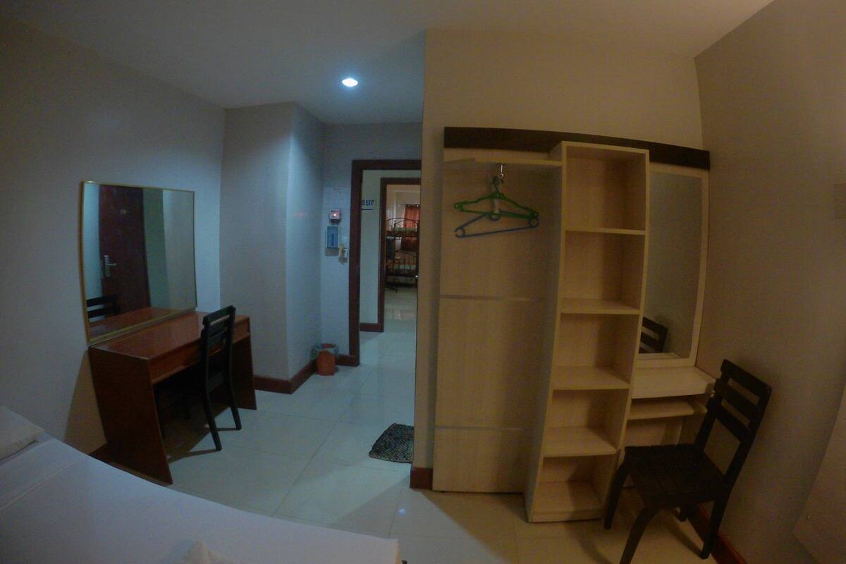 A room with a desk, chair, and a wardrobe with shelves.