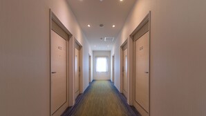 A hotel hallway with doors numbered 613 and 614, carpeted flooring, and a window at the end. - Business Hotel Hayashiso (Miyazaki)