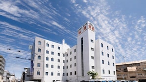 A multi-story hotel with a prominent tower featuring signage. - Business Hotel Hayashiso (Miyazaki)