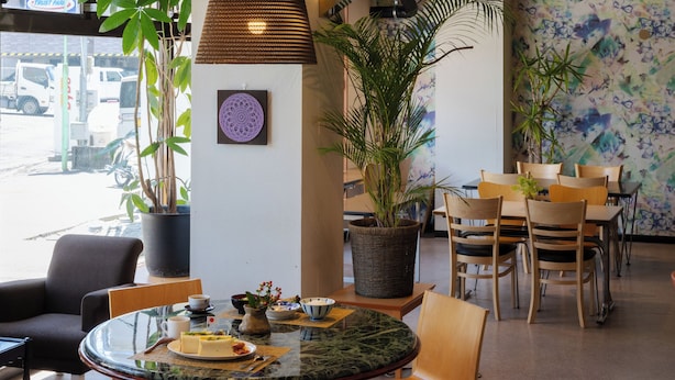 A restaurant with a round marble table, wooden chairs, and potted plants. - Business Hotel Hayashiso (Miyazaki)