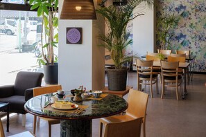 Un restaurante con una mesa redonda de mármol, sillas de madera y plantas en macetas.