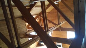 Interior em madeira com vigas aparentes e um ventilador de teto.