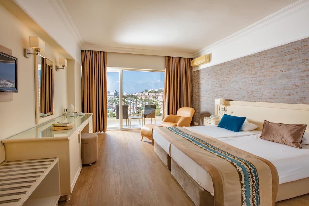Habitación de hotel con una cama grande, un escritorio, una silla, una mesita y vistas a la ciudad.