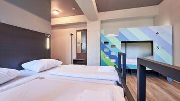 Habitación de hotel con dos camas, un espejo y una pared con literas numeradas.