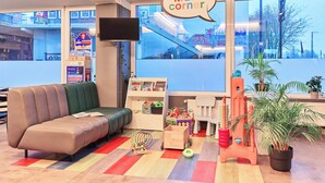 Ein Kinderspielbereich mit einer Couch, Spielzeug und einem Fernseher.