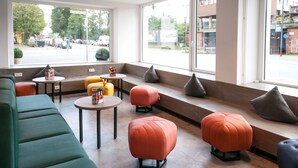 Ein modernes Interieur mit Sitzbereichen, Tischen und großen Fenstern mit Blick auf die Straße.