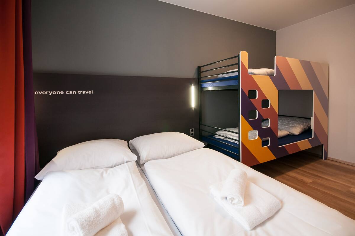 Een kamer met een stapelbed en een eenpersoonsbed, beide met wit beddengoed.