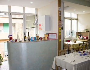 A restaurant with a bar area, tables set for dining, and a view of the street outside. - Ostello Bella Napoli (Naples)