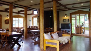 A spacious room with high ceilings, wooden beams, and large windows. There are multiple tables and chairs arranged for dining or meetings. - Gassan Pole Pole Farm (Nishikawa)