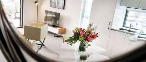 En moderne stue med sofa, sofabord og en vase med blomster.