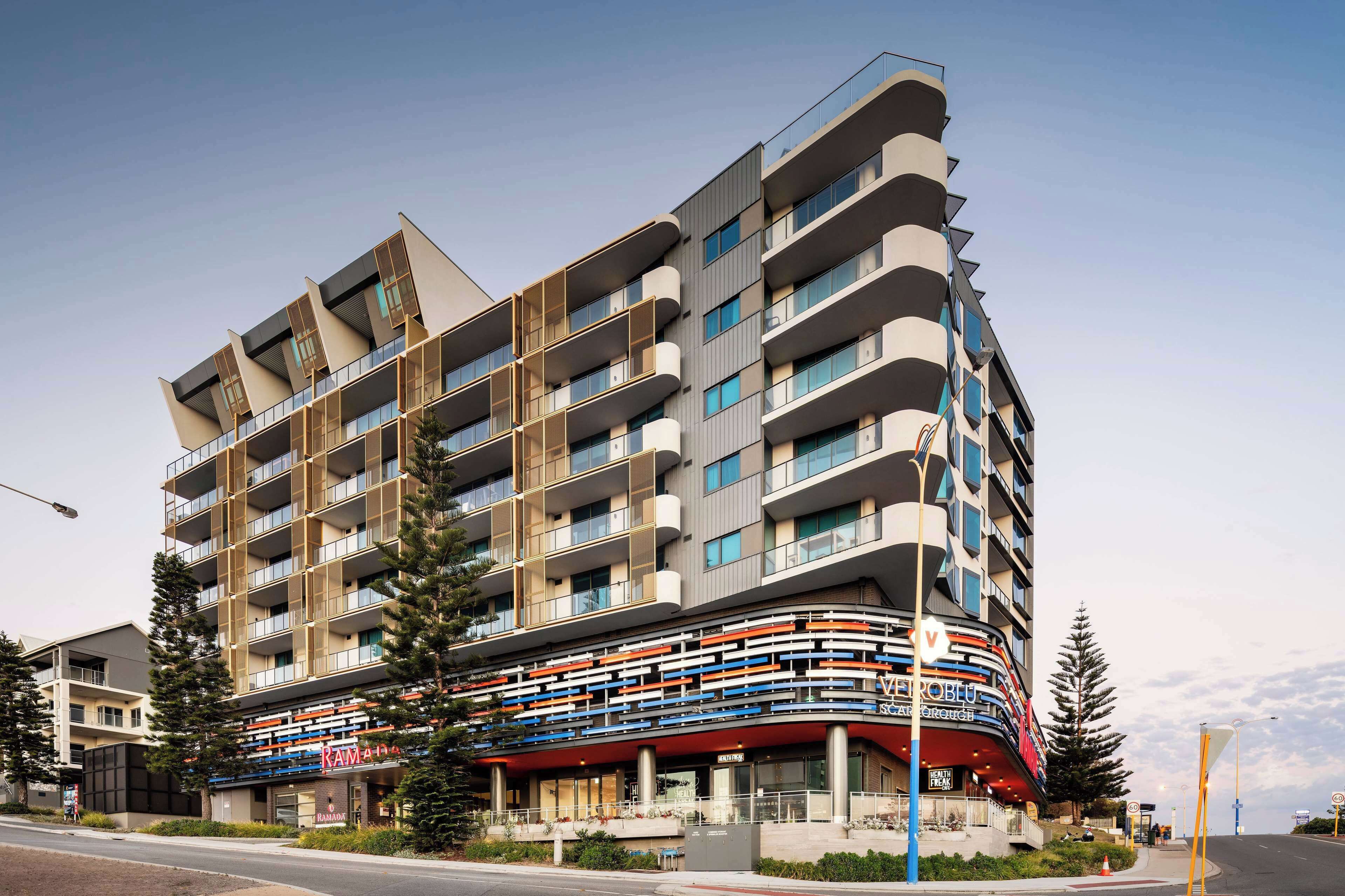 A multi-story hotel with balconies, a curved facade, and a visible restaurant named "Ravina."