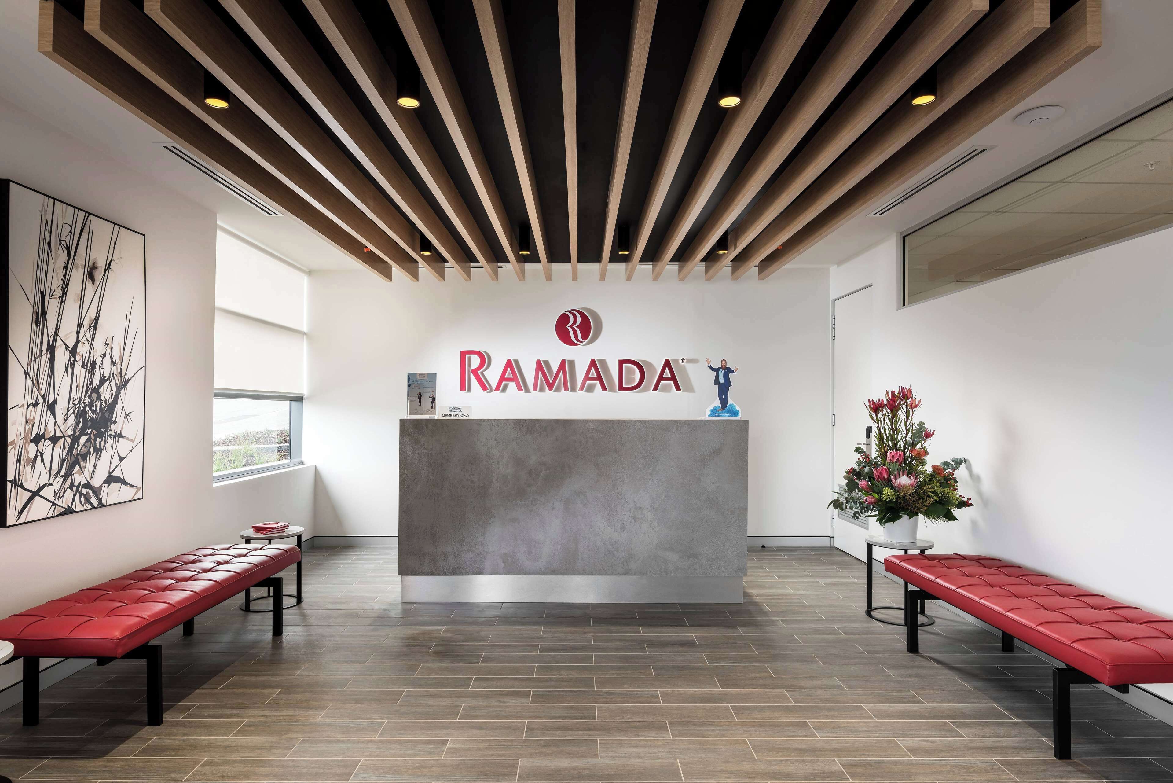 A reception area with a modern design, featuring a reception desk, benches, and a ceiling with wooden slats.