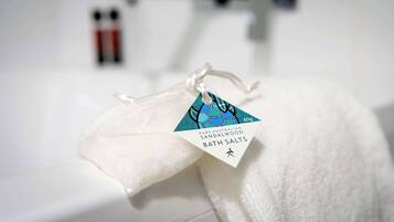 Een witte badmat met een etiket waarop staat: 'Pure Australian Sandalwood Bath Salts'.